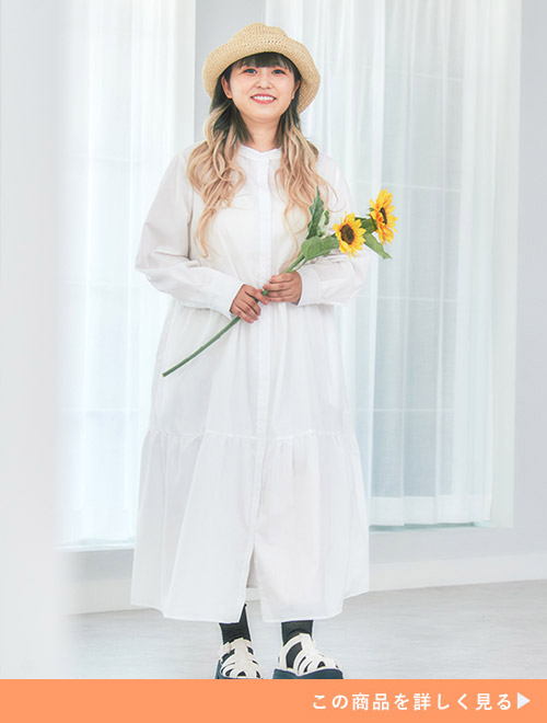ティアードデザインの白シャツワンピースを着る女性