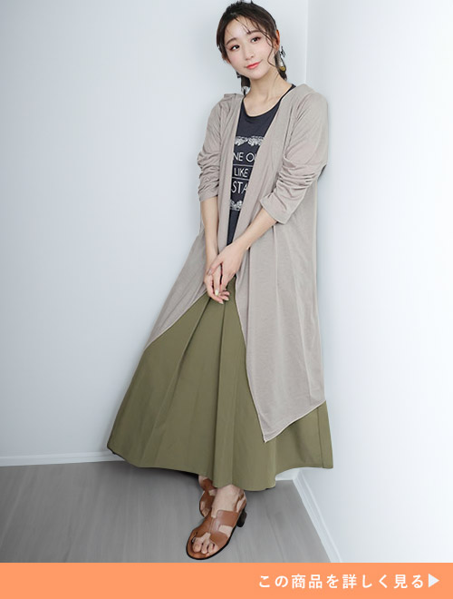 ブラックTシャツとグリーンフレアスカートのコーデにグレージュのロングカーディガンを羽織る女性