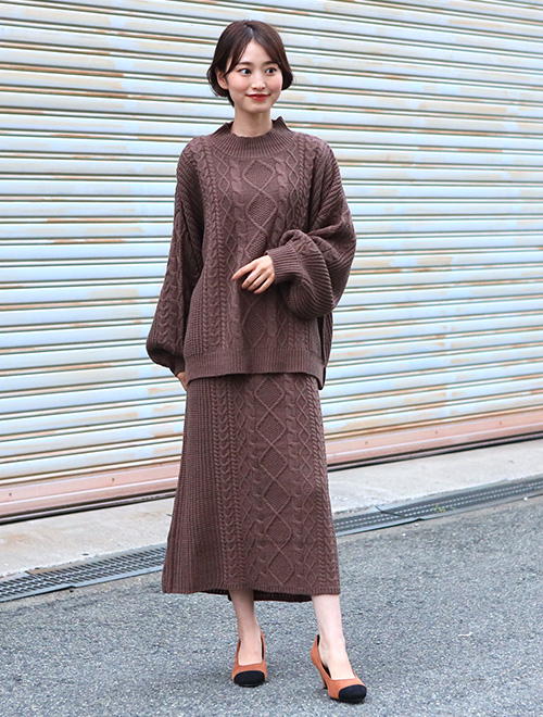 チョコレートブラウンのケーブル編みニットアップを着る女性