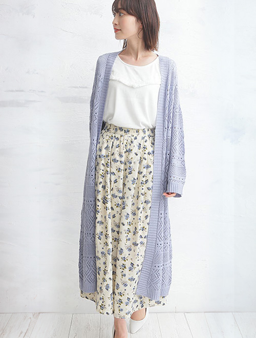 白トップスと小花柄スカートのコーデに、透かし編みロングカーディガンを羽織った女性