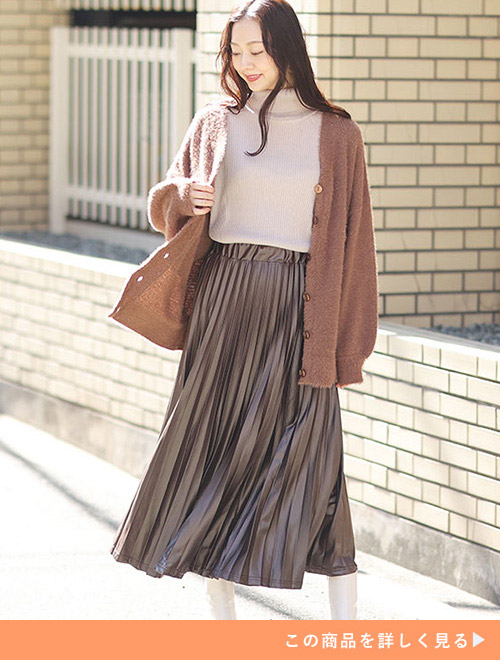 ベージュのタートルネックニット×茶色のプリーツスカートに、モカ色のカーディガンを羽織る女性