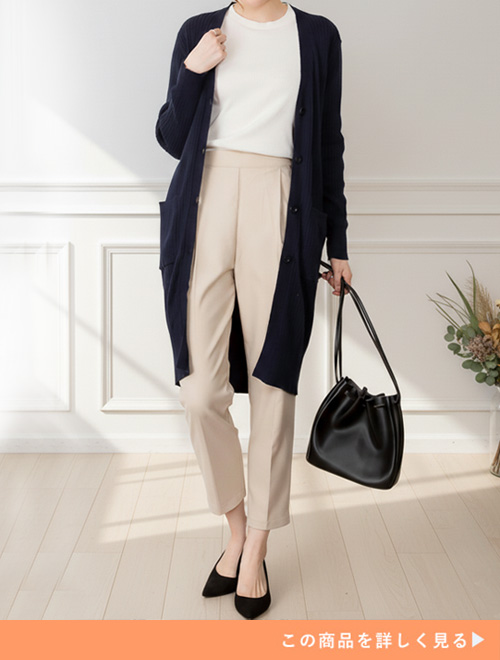 ベージュパンツとホワイトトップスのコーデにブラックロングカーデを羽織る女性