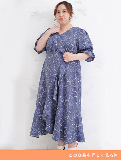くすみブルーの生地に線画花柄模様を描いたカシュクールデザインのワンピースを着る女性