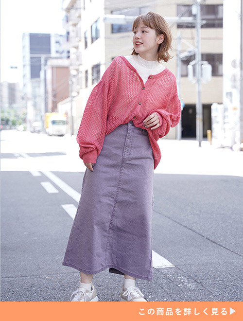 白トップス×紫のデニム生地タイトスカートにピンクの透かし編みカーディガンを羽織る女性