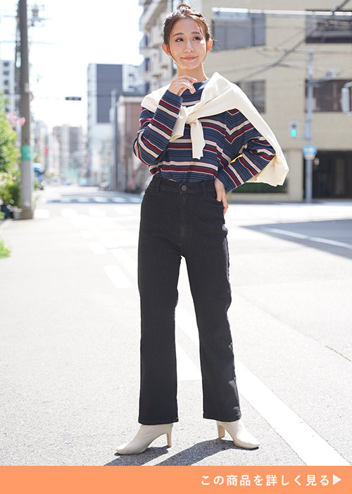 ブラックデニムとマルチボーダー柄のトップスのコーデにホワイトカーデを羽織る女性