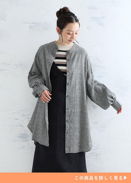 ボーダー柄トップス×黒のジャンスカに、グレンチェック柄チュニックシャツを前開きで羽織る女性
