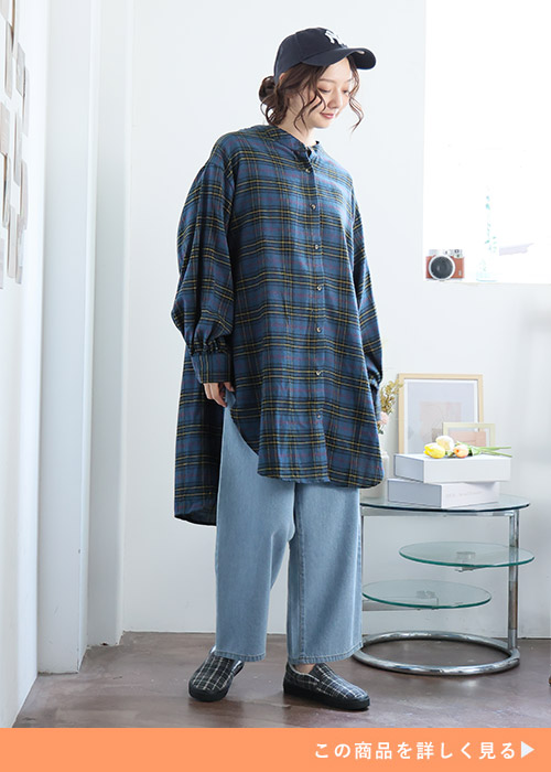 ネルシャツ素材のダークブルーのチェック柄チュニック×薄色デニムパンツを着る女性