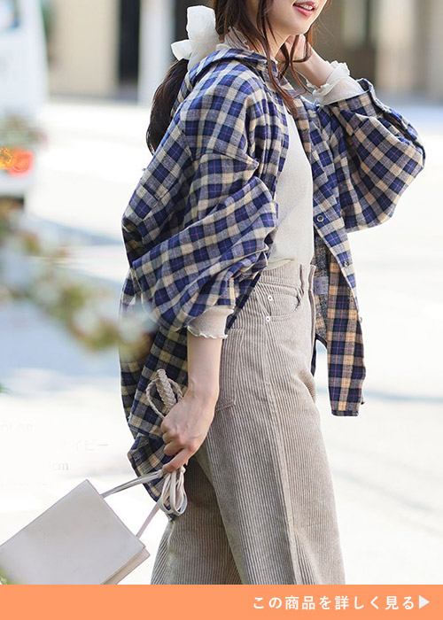 ベージュ系のシアートップスとパンツに、ベージュ×ネイビーのチェック柄シャツを羽織る女性