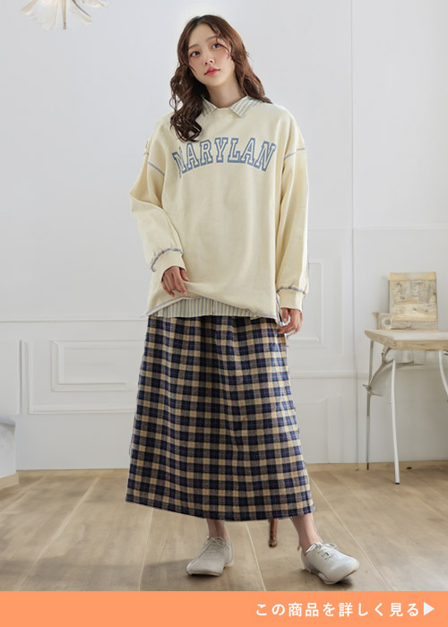 薄いイエロートップスにベージュ×ネイビーのチェック柄フランネル素材のスカートを履く女性