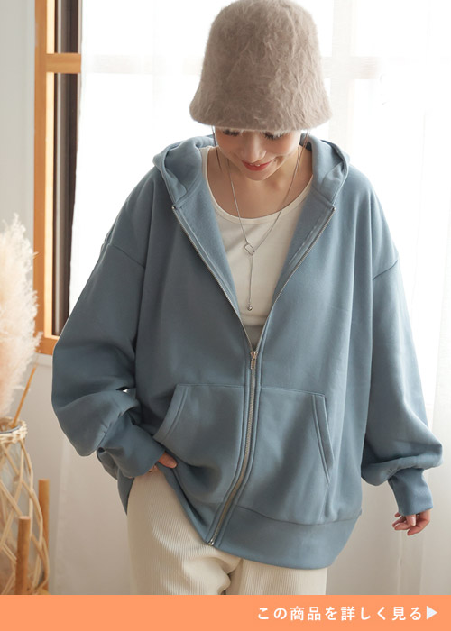 ブルーのパーカーに白のパンツを着る女性