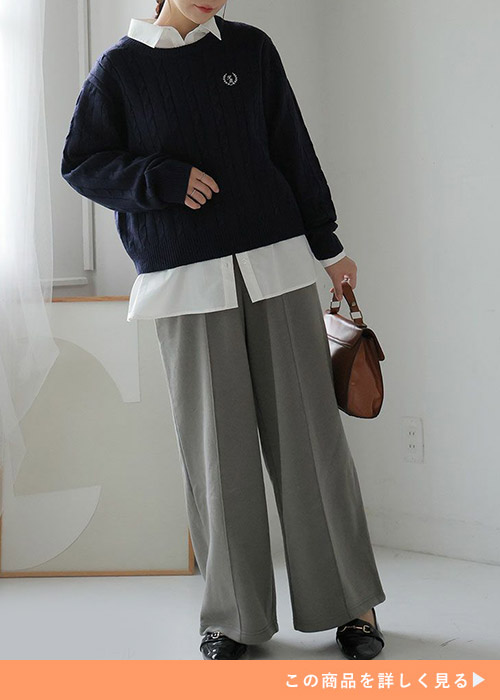 グレーのパンツに黒のトレーナーにシャツをレイヤードして着る女性