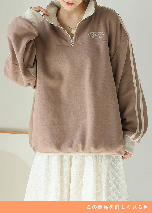 白のスカートにブラウンのジップスウェットを着る女性