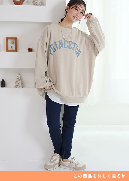 ネイビーのパンツとベージュのロゴトレーナーを着る女性