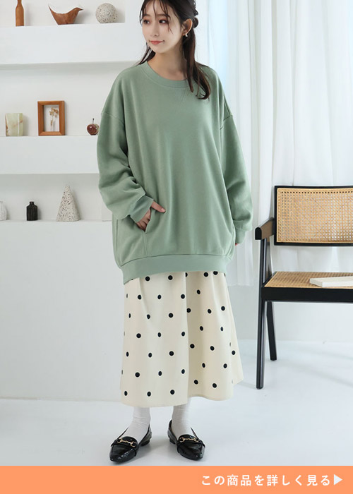 ドットのスカートとグリーンのトレーナーを着る女性
