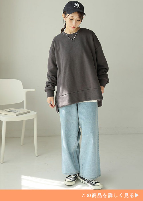 デニムパンツとグレーのトレーナーを着る女性